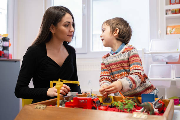 Psychological counselor examines child boy's behavior while he is playing with toys