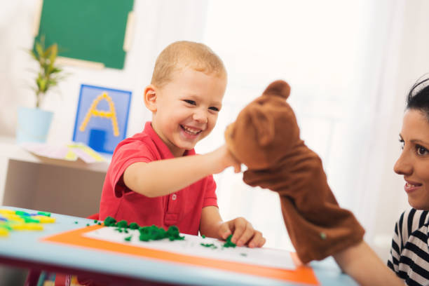 Little boy during lesson with his speech therapist. Learning through fun and play